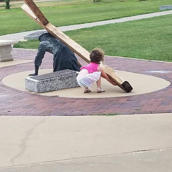 Niña ayuda a cargar la cruz